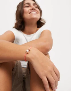 Pulsera de hilo fucsia con perla shell fornitura bañada en oro 18k.